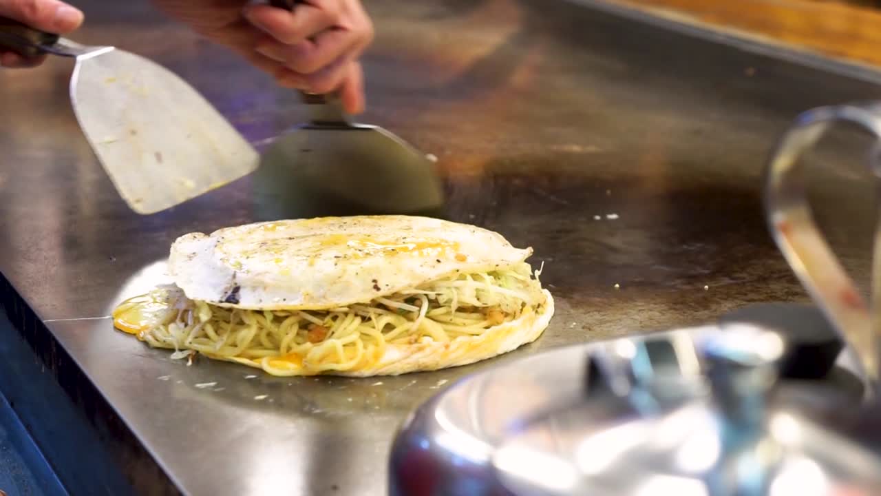 Detail of hands cooking Okonomiyaki. Handheld, shallow focus