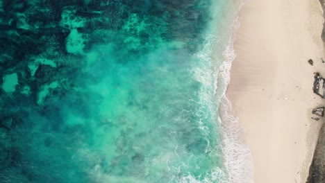 ocean waves crashing on sandy shore at diamond beach in nusa penida, bali, indonesia