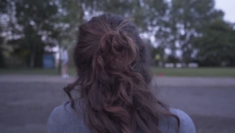 close view of the head of a woman from her back watching her friends playing basketball