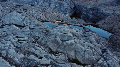 puddles on rocks reflecting mountains