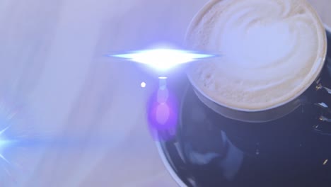 animation of lens flares moving over high angle view of coffee cup on table