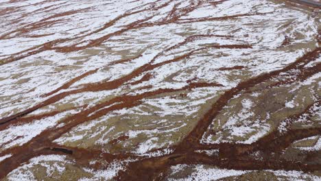 streaks of brown land created by dried up rivers in snowy glacier plain