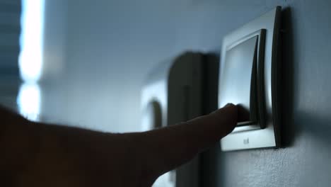 human hand turn off power button on the wall