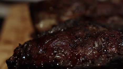 thick juicy steaks sizzle in outdoor barbeque grill in backyard, extreme close up