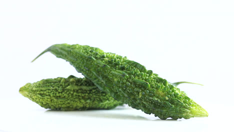 sliced-bitter-gourd-and-whole-biter-gourd-bitter-melon-in-white-background-rotating-side-shot