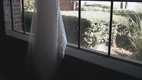 traditional wedding dress for bride hanging in window, dolly shot