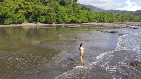 Beautiful-female-model-stands-on-beach-looking-out-over-ocean,-Costa-Rica