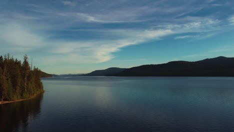 paisaje de puesta de sol de un lago con montañas en el fondo - toma aérea de un dron