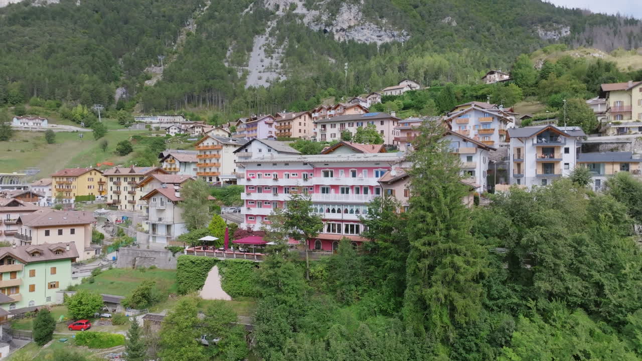 Aerial video moving away from a hotel in the town of Molveno in northern Italy with the Dolomite mountains in the background.