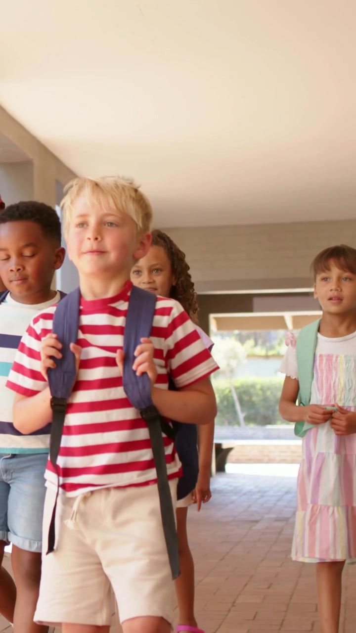 Vertical video: Door opening, blond boy in striped tee leading group with packs through porch out