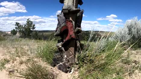 cowboy boots hanging on a wooden post in the country side on a sunny day