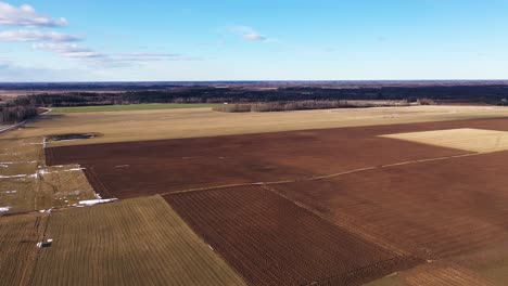 Campos-Arados-En-Un-Vasto-Campo-En-Un-Día-Despejado,-Toma-Aérea-De-Drones