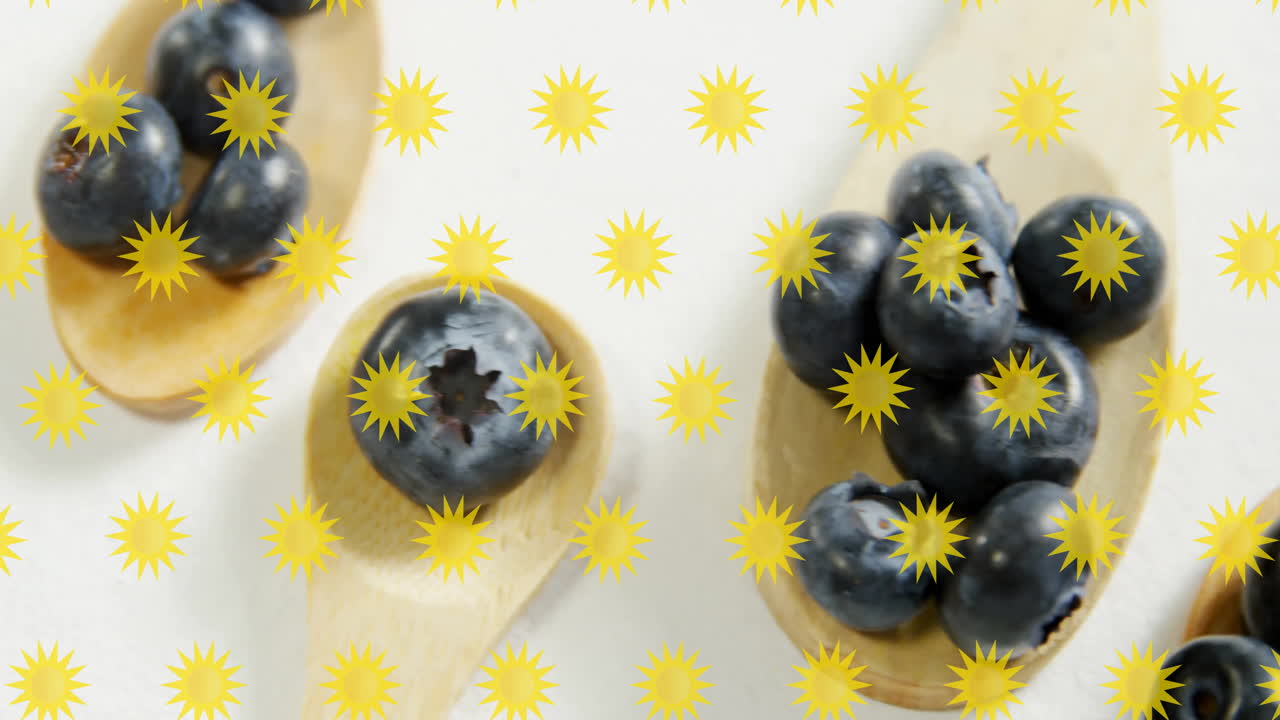 Blueberries on wooden spoons with yellow starburst background