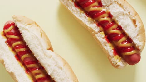 video of hot dogs with mustard and ketchup on a yellow surface