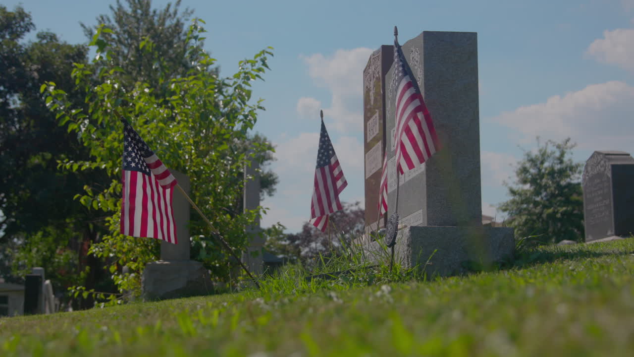 Headstones at Pelham Cemetery, The Bronx, New York. US flag beside a headstone. On a sunny day.