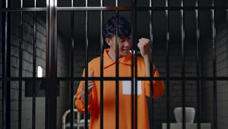 prisionero masculino asiático con esposas rotas gritando meta celebrando mientras está de pie en la cárcel