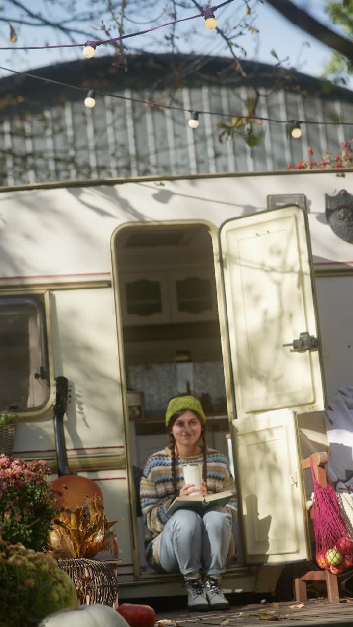 Donna che si rilassa e legge in un camper in una giornata autunnale