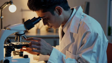 a young scientist or student examines samples with a microscope in a lab