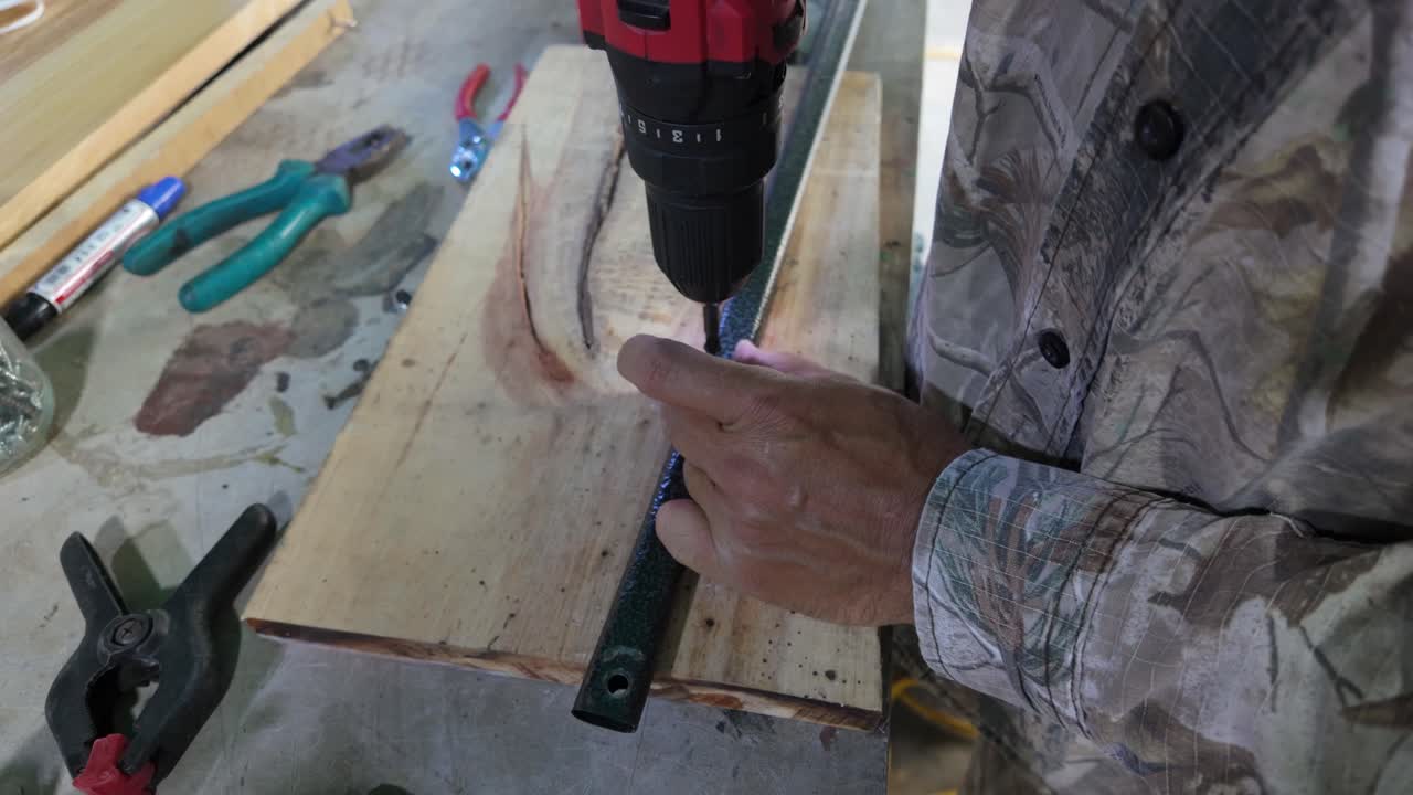 Man hands used a cordless drill with LED light to make a hole in metal rod