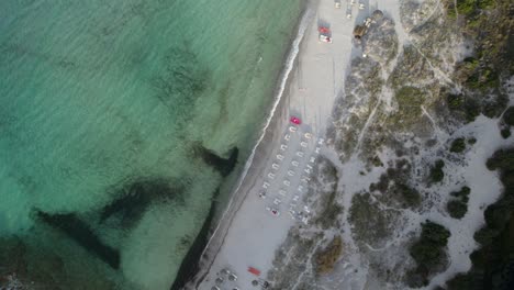 toma aérea de arriba hacia abajo de una hermosa playa de arena completamente vacía debido al bloqueo de la pandemia del coronavirus en la costa esmeralda cerca de porto cervo, cerdeña, italia