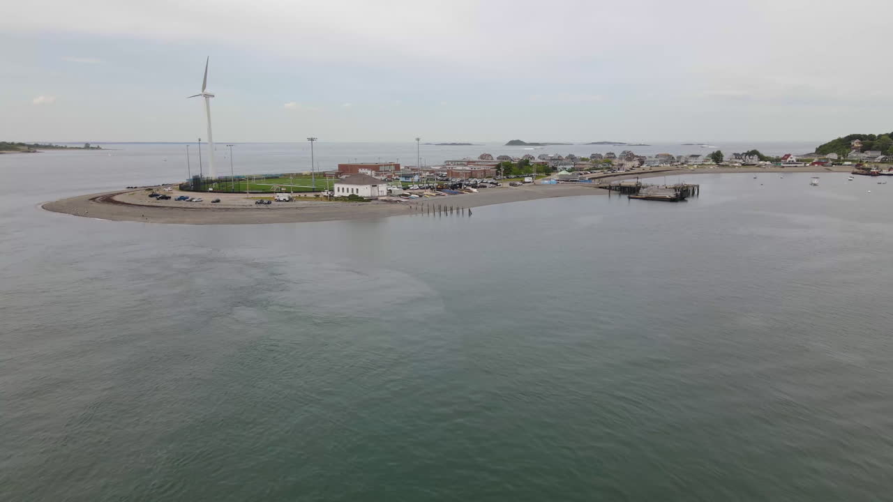 drone volando hacia la península con turbina eólica y edificio recreativo