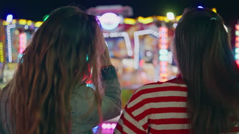 closeup fun friends resting colourful amusement luna park. two girls at carnival