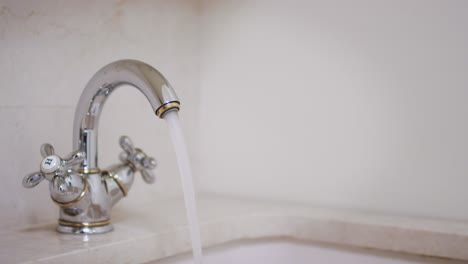 woman hand turning knob and opening water tap in bathroom