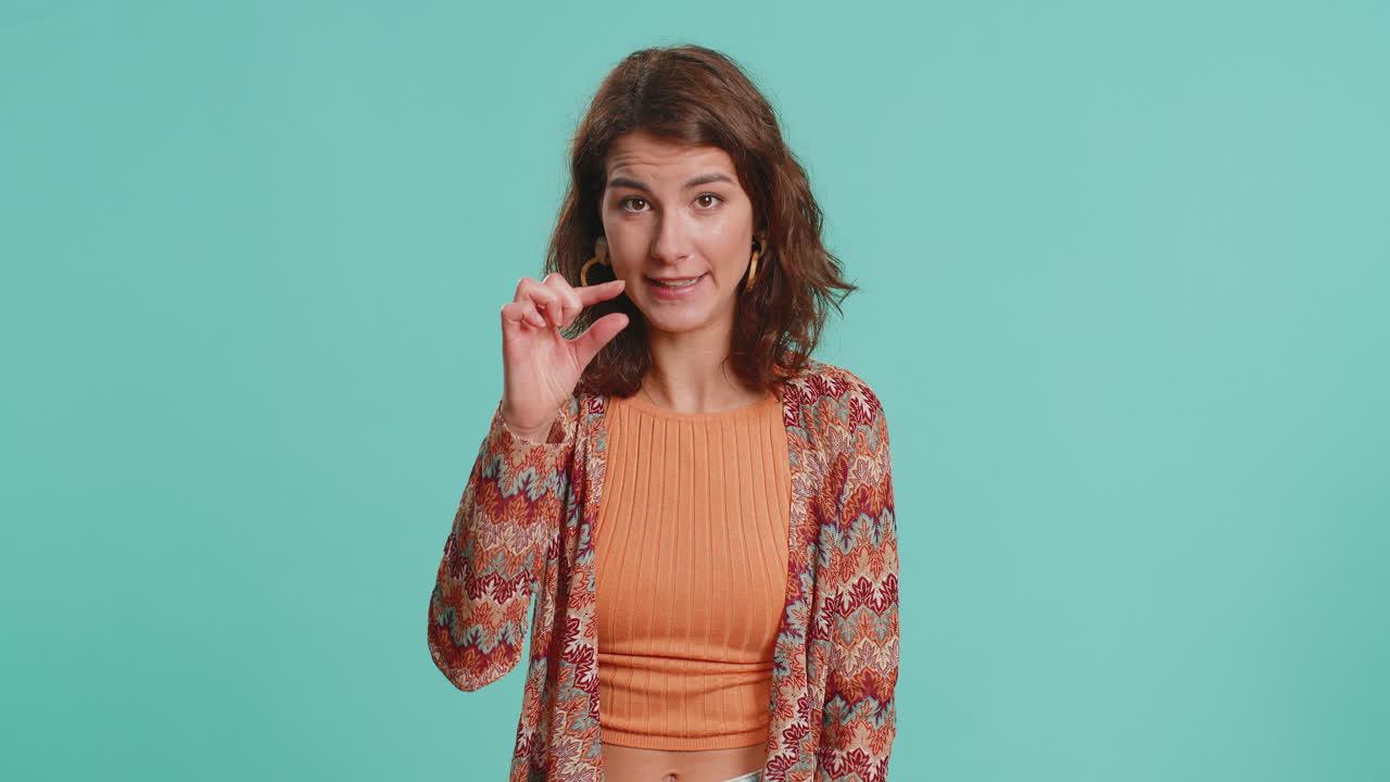 mujer mostrando un pequeño gesto con una sonrisa escéptica mostrando un signo mínimo midiendo un tamaño pequeño