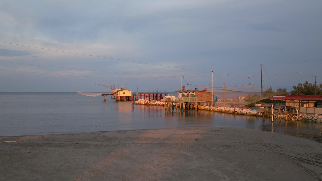 vista aérea de cabañas de pesca a orillas del estuario al atardecer, máquina de pesca italiana, llamada "trabucco", lido di dante, ravenna cerca del valle de comacchio