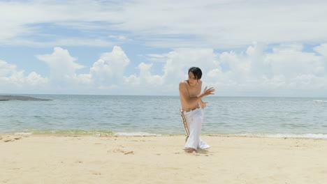 un tipo bailando capoeira en la playa.