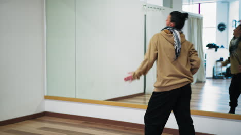 woman practices dancing to music in dance school