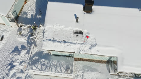 vista aérea alrededor de paneles solares parcialmente limpiados en un techo de casa nevado, día de invierno