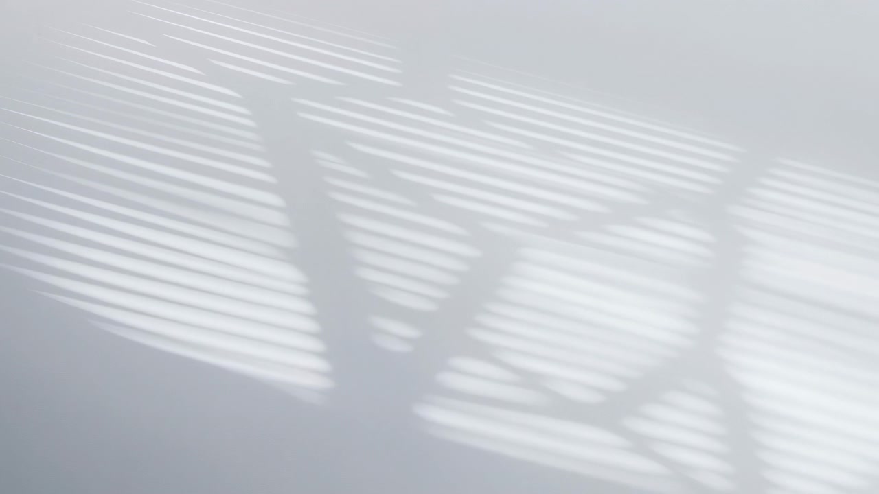 Alternating bright and dark horizontal bands of sunlight fall diagonally across smooth pale surface as light passes through horizontal blinds, creating soft contrast, gentle texture, calm interior