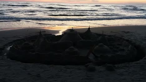 un castillo de arena mojada en la playa al atardecer