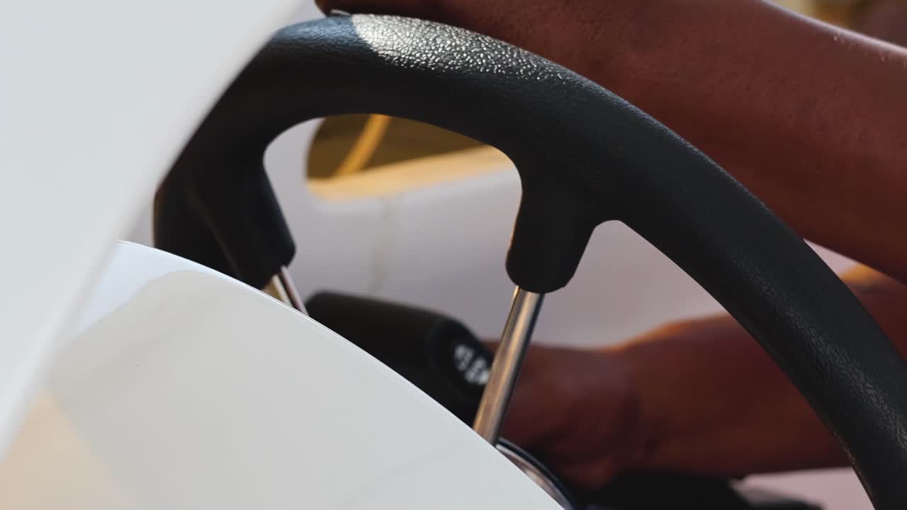 Detailed view of hands gripping and maneuvering a boat's steering wheel in various positions.
