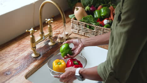 washing fresh bell peppers in kitchen sink, preparing healthy meal at home