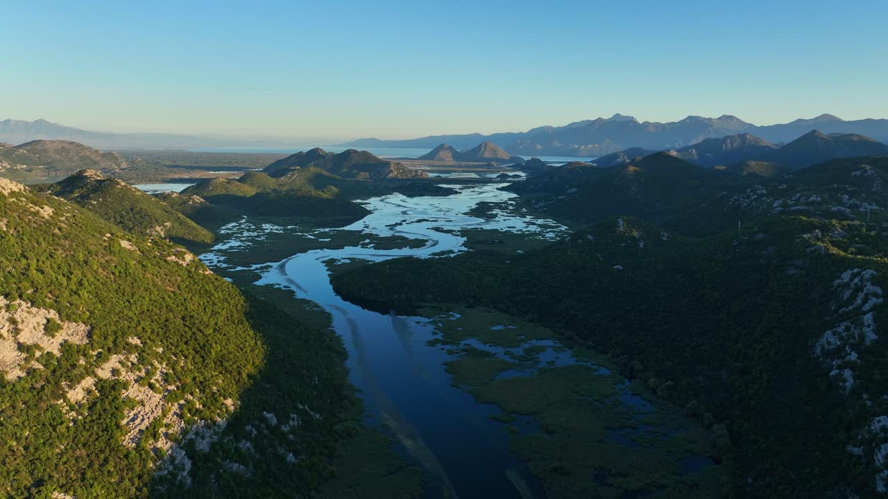 Skadar Lake showing winding waterways and lush landscape during golden hour, aerial pullback