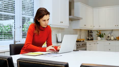 Woman-using-laptop-in-kitchen-4k