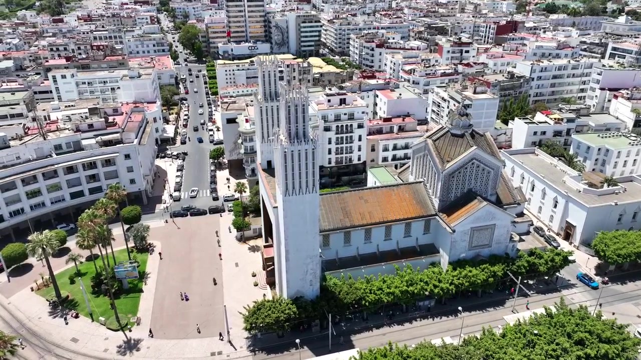 Vista aérea ampla do centro de Rabat, Marrocos, mostrando arquitetura urbana densa, linhas de bonde, ruas movimentadas, espaços públicos e o Oceano Atlântico no horizonte