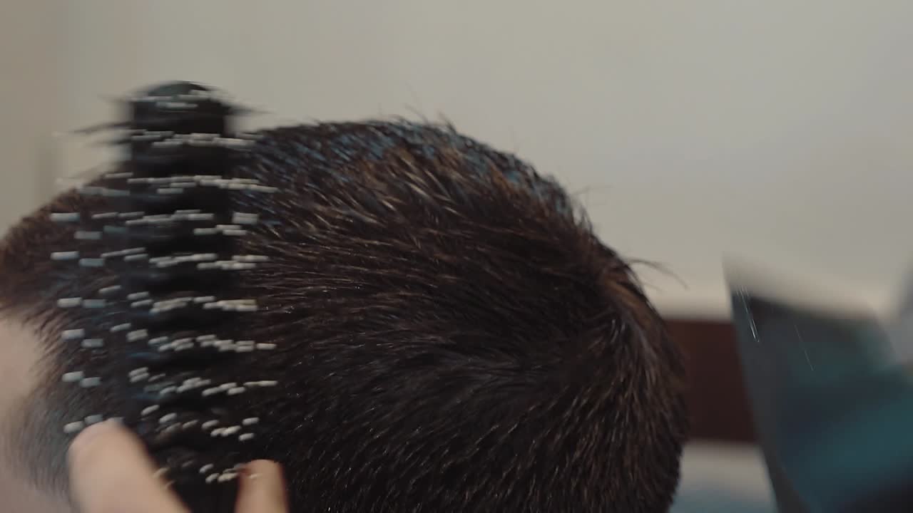 젊은 남자가 이발소에서 머리카락을  ⁇ 고 있습니다.