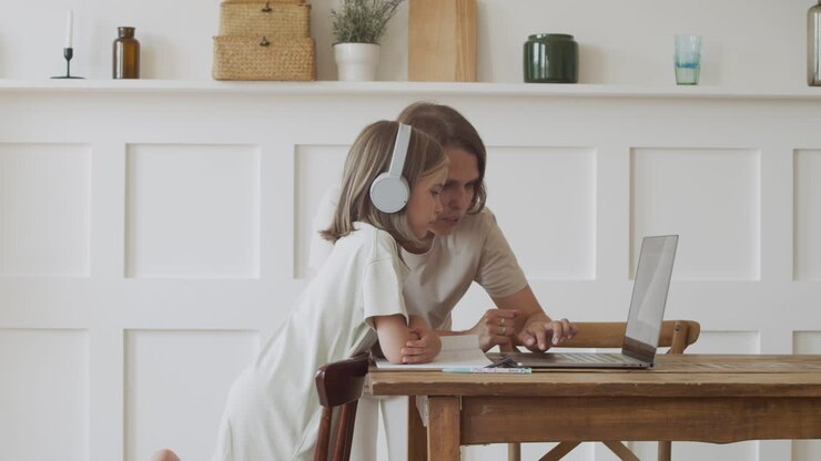 Una simpatica bambina bionda con le cuffie e sua madre cercano contenuti online sul laptop