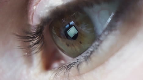 extreme close up, womans eye reflecting social media feed on laptop screen