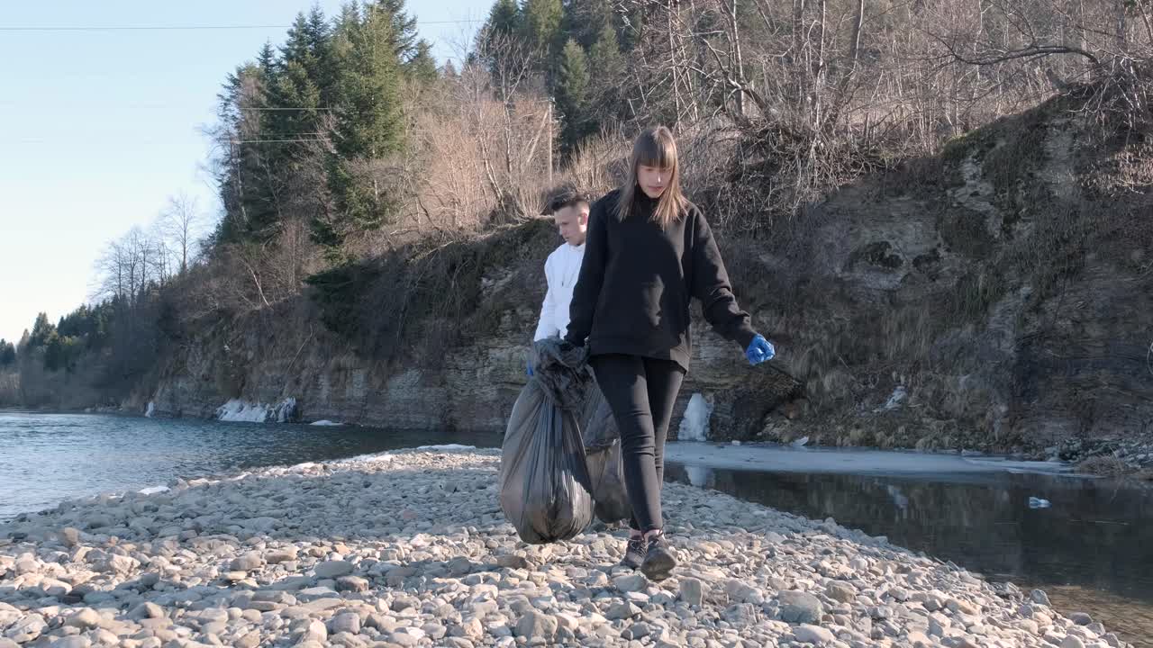 Lavoro di squadra per la pulizia della plastica sulla spiaggia. Volontari raccolgono rifiuti in un sacco della spazzatura. Concetto di inquinamento da plastica e problema ambientale. Pulizia volontaria della natura dalla plastica. Rendere il pianeta più verde.