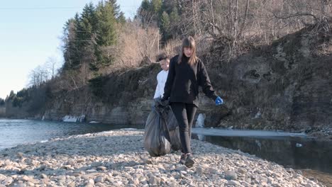 teamwork cleaning plastic on the beach. volunteers collect trash in a trash bag. plastic pollution and environmental problem concept. voluntary cleaning of nature from plastic. greening the planet