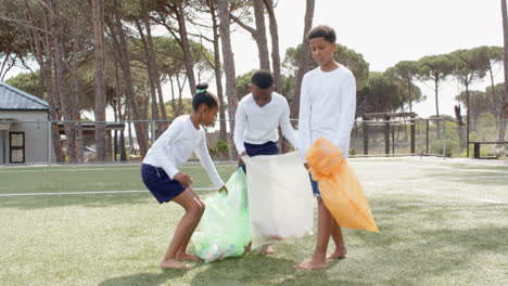 multiracial students cleaning up park, holding colorful bags, enjoying teamwork outdoors