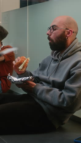 man eating a burger in an office