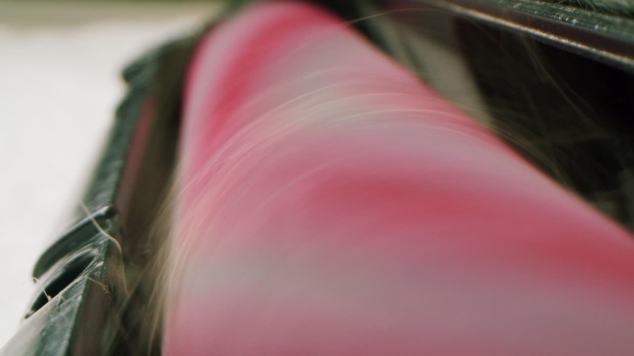 Nærbillede af fibre, der spinder på en lyserød industriel rulle