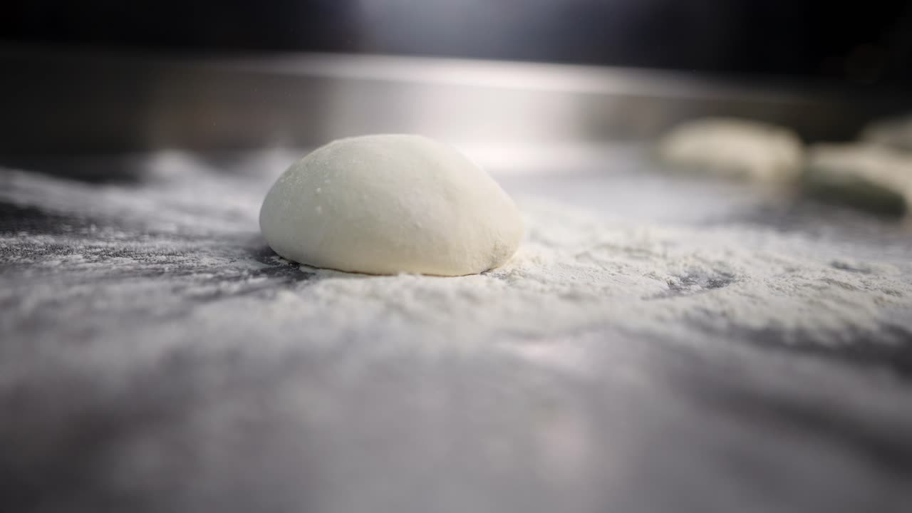 Unique close up view of dough falling over flour in slow motion in a restaurant kitchen