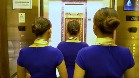 three flight stewardesses stepping out of elevator back shot 4k