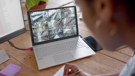 African-american-female-security-officer-watching-cctv-camera-views-on-laptop,-slow-motion